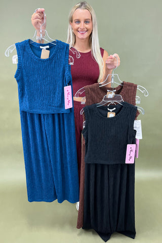 Woman holding two dresses on hangers against a plain background