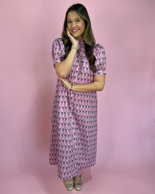 Woman wearing a pink patterned dress against a pink background