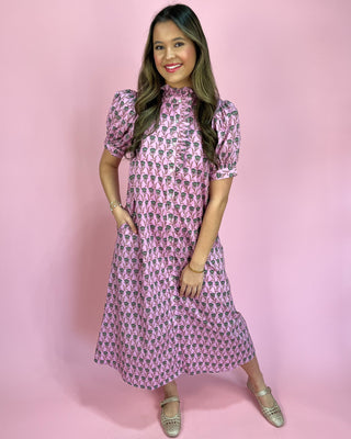 Woman wearing a pink patterned dress against a pink background