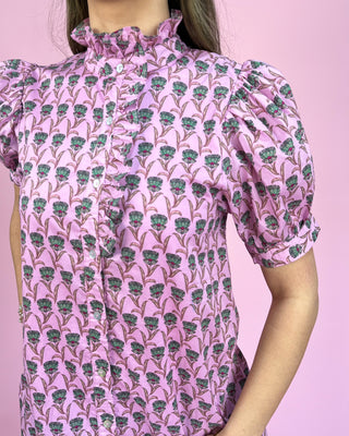 Person wearing a pink floral patterned dress against a pink background