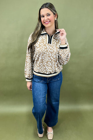 Woman wearing a leopard print sweater and blue jeans on a green background