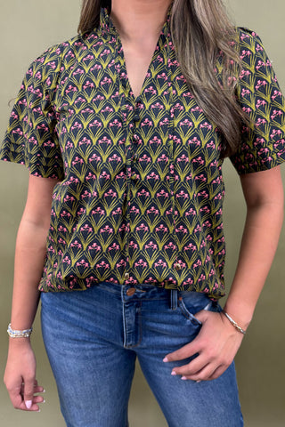 Person wearing a patterned shirt and jeans against a plain background