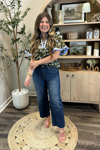 Woman standing in a room with a plant and wooden cabinet in the background