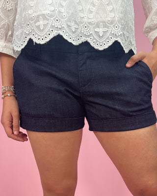 Navy shorts worn by a person on a pink background