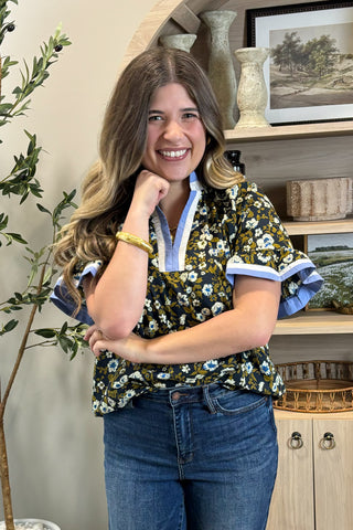 Woman wearing a floral blouse and jeans in a home setting