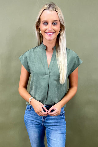 Woman wearing a green blouse and blue jeans against a green background