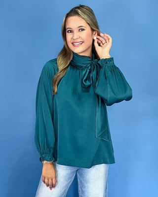 Emerald green satin blouse with a tie neck, long balloon sleeves, and gathered cuffs, shown on model.