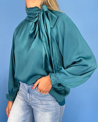 Emerald green satin blouse with a tie neck, long balloon sleeves, and gathered cuffs, shown on model.