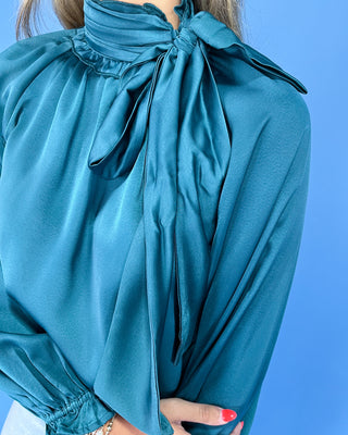 Emerald green satin blouse with a tie neck, long balloon sleeves, and gathered cuffs, shown on model.