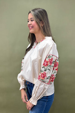 Woman wearing a white blouse with floral embroidery on a plain background