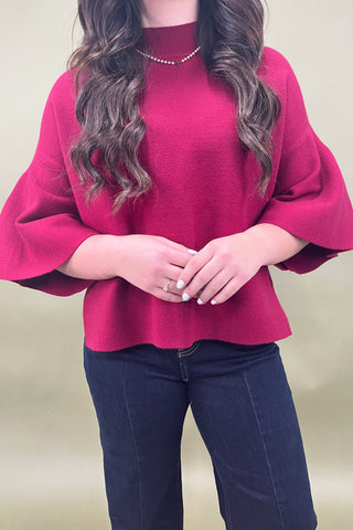 Person wearing a red sweater and blue jeans against a plain background