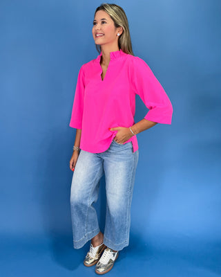 Hot pink blouse with a ruffle split neckline, three-quarter balloon sleeves, and relaxed fit, shown on model.
