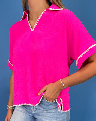 Hot pink top with white whipstitch trim, split neckline, short sleeves, and relaxed fit, shown on model.