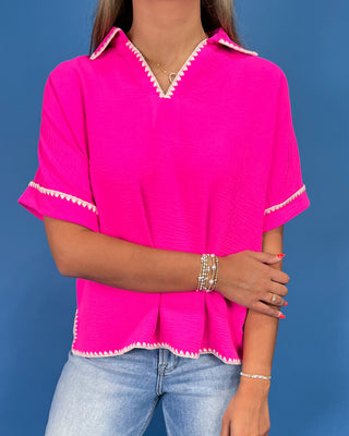 Hot pink top with white whipstitch trim, split neckline, short sleeves, and relaxed fit, shown on model.