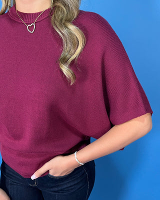 Burgundy short sleeve dolman knit sweater top with a mock neckline and relaxed fit.
