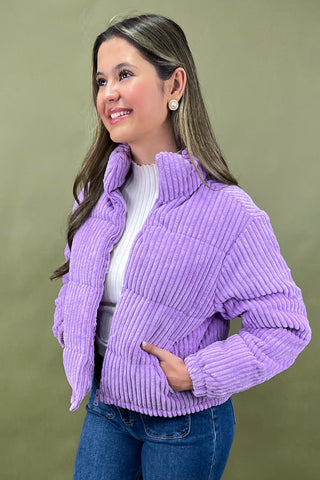 Woman wearing a purple ribbed sweater against a green background