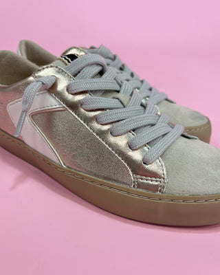 Silver sneaker with a brown sole on a pink background