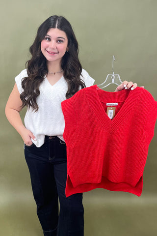 Woman holding a red sweater vest against a green background