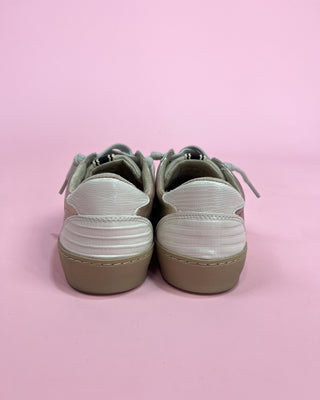 Pair of sneakers with white soles on a pink background