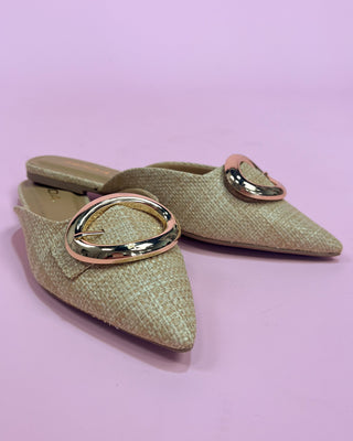 Pair of green pointed-toe shoes with gold buckles on a pink background