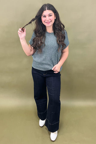 Woman posing with one hand in her hair against a plain background
