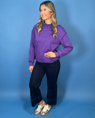 Purple long sleeve mock neck sweatshirt top with a relaxed fit and raw edge details.