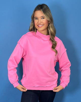 Hot pink long sleeve mock neck sweatshirt top with raw edge details and a relaxed fit.