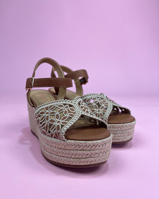 Pair of sandals with woven sole and lace-up design on a pink background