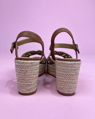 Pair of sandals with woven soles on a pink background