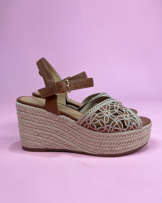 Woven wedge sandal with a strap on a pink background
