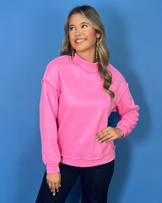 Hot pink long sleeve mock neck sweatshirt top with raw edge details and a relaxed fit.