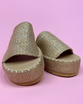 Gold glittery sandals on a pink background