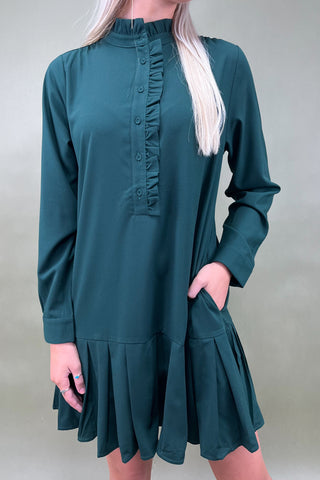 Teal dress with long sleeves and ruffled neckline worn by a person against a plain background