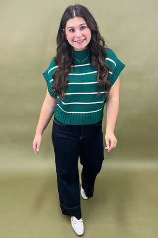 Woman wearing a green striped sleeveless sweater against a gold background