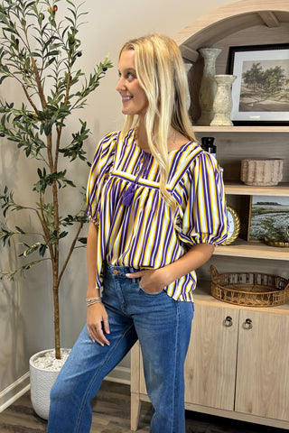 Woman wearing a striped shirt and jeans standing in a room with decor elements.