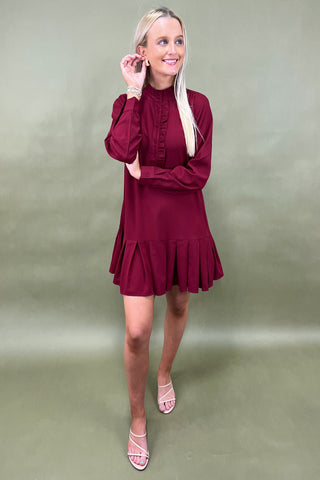 Woman wearing a burgundy dress against a plain background