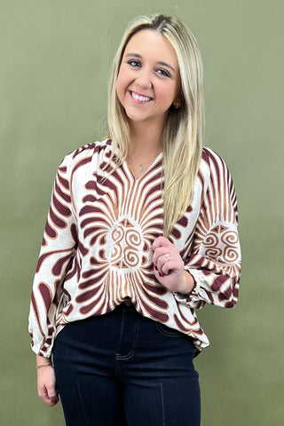 Woman wearing a patterned blouse against a green background