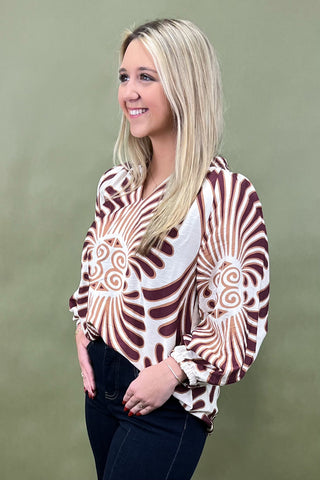Woman wearing a patterned blouse against a green background