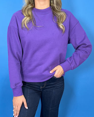 Purple long sleeve crewneck sweatshirt with a relaxed fit, drop shoulders, and ribbed neckline and cuffs.