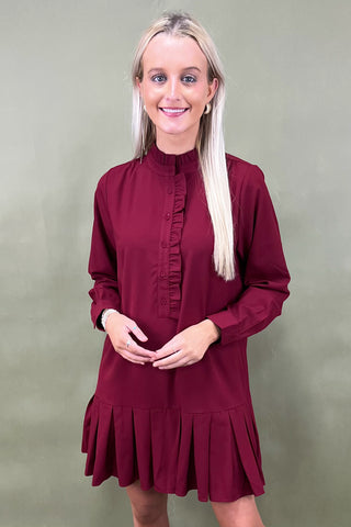 Woman wearing a burgundy dress against a plain background