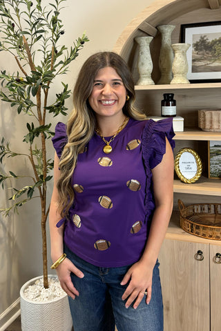 Woman wearing a purple top with gold accents in a home setting