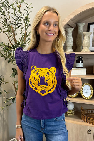 Woman wearing a purple shirt with a yellow tiger logo indoors.