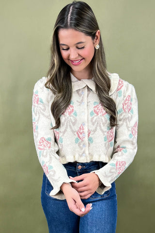 Woman wearing a floral blouse and blue jeans against a green background