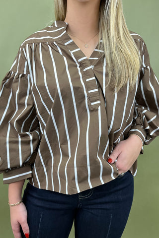 Woman wearing a brown and white striped blouse against a green background