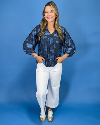 Navy blue floral textured blouse with a V-neck and three-quarter balloon sleeves, shown on model.