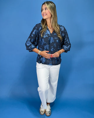Navy blue floral textured blouse with a V-neck and three-quarter balloon sleeves, shown on model.