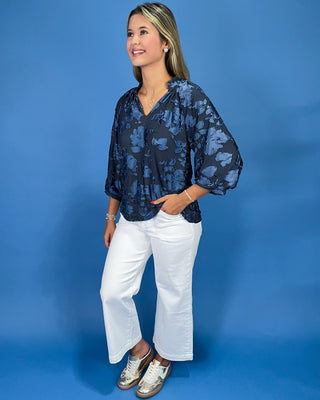 Navy blue floral textured blouse with a V-neck and three-quarter balloon sleeves, shown on model.