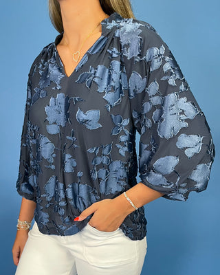 Navy blue floral textured blouse with a V-neck and three-quarter balloon sleeves, shown on model.
