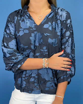 Navy blue floral textured blouse with a V-neck and three-quarter balloon sleeves, shown on model.