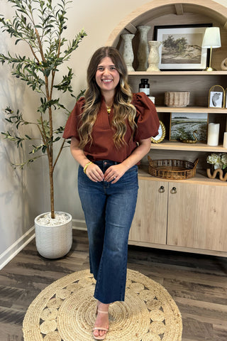 Woman standing in a room with a plant and wooden cabinet